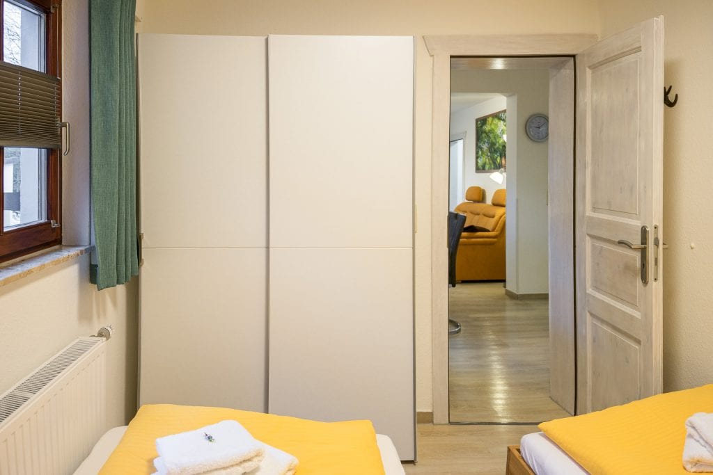 Gemütliches Zimmer mit Einzelbetten und Schrank.