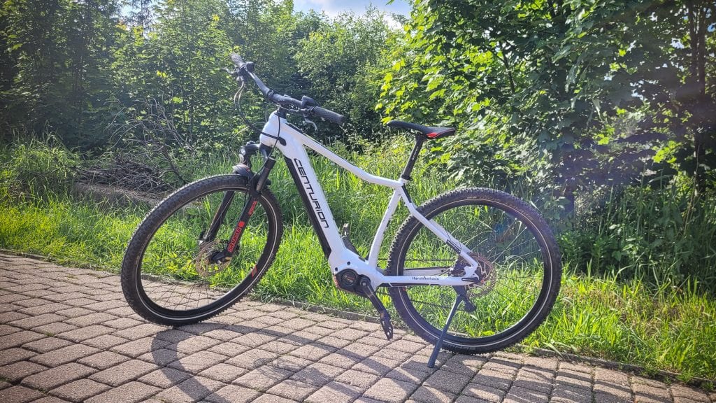 Weißes Mountainbike auf gepflastertem Weg bei Sonnenschein.