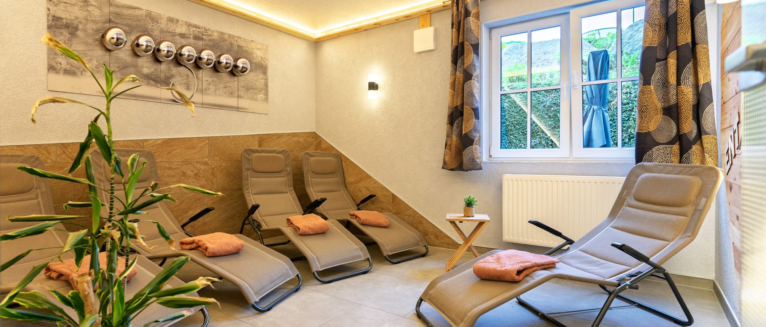 Gemütlicher Entspannungsraum mit Liegen und Pflanzen.