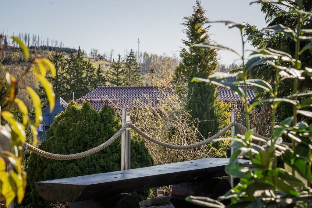 Blick über Garten mit Hausdach und Waldhügeln