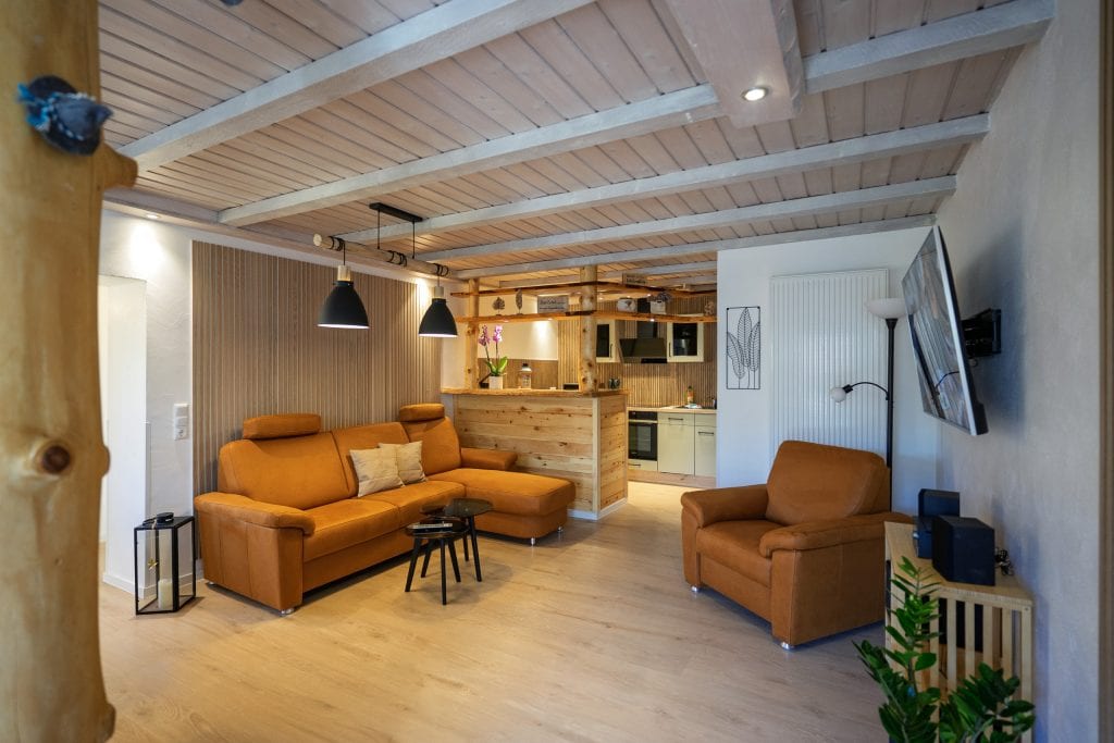 Gemütliches Wohnzimmer mit offener Küche und Holzbalkendecke