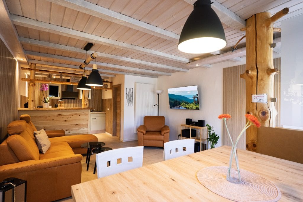 Gemütliches Wohnzimmer mit Holzdecke und offener Küche