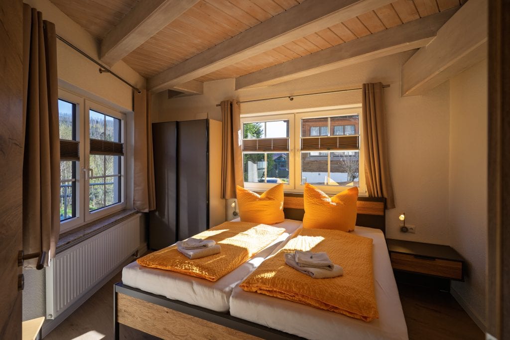 Helles Schlafzimmer mit Holzdecke und gelben Betten