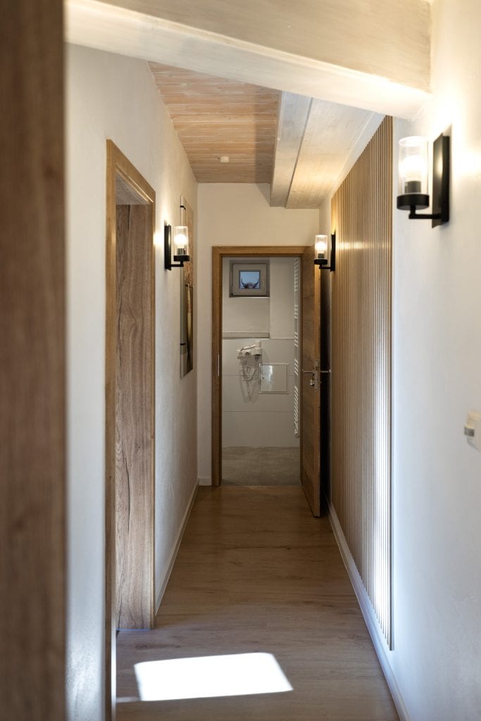 Schmaler Flur mit Holzboden und Wandlampen