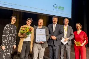 Menschen mit Blumenstrauß und Auszeichnung auf Bühne