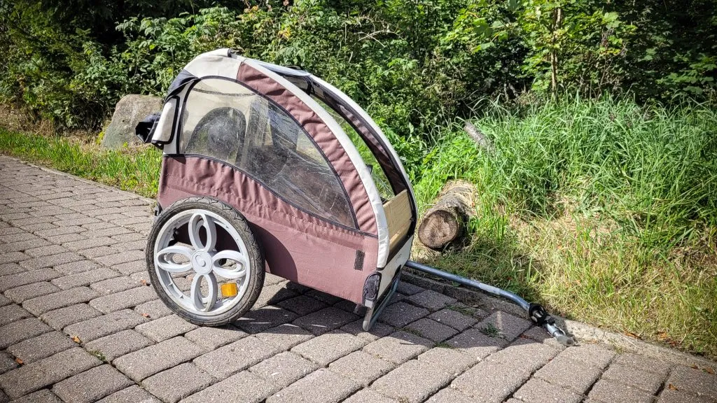 Brauner Fahrradanhänger auf gepflastertem Weg im Freien