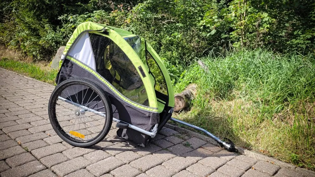 Grüner Fahrradanhänger auf Gehweg