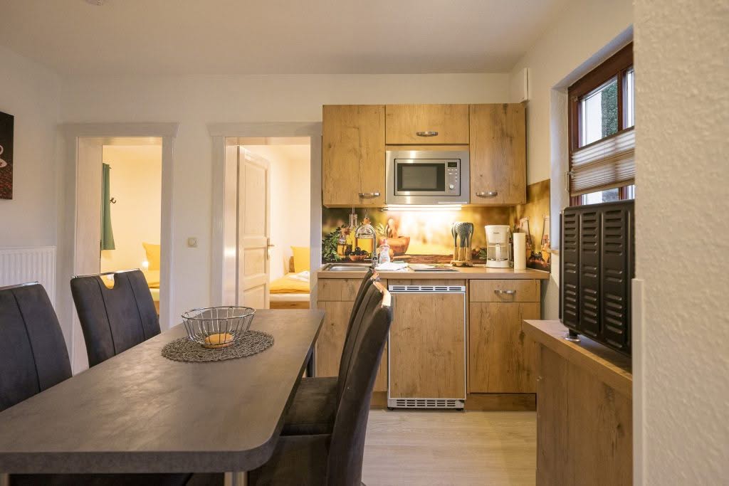 Moderne køkkenområde med spisebord og træmøbler.