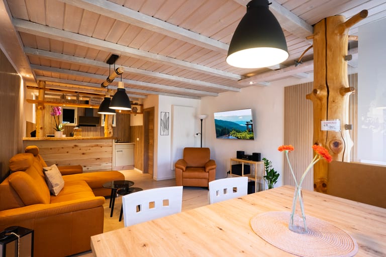 Gemütliches Wohnzimmer mit Holzdecke und offener Küche