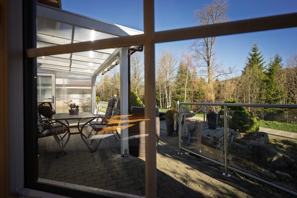 Overdækket terrasse med bord og haveudsigt