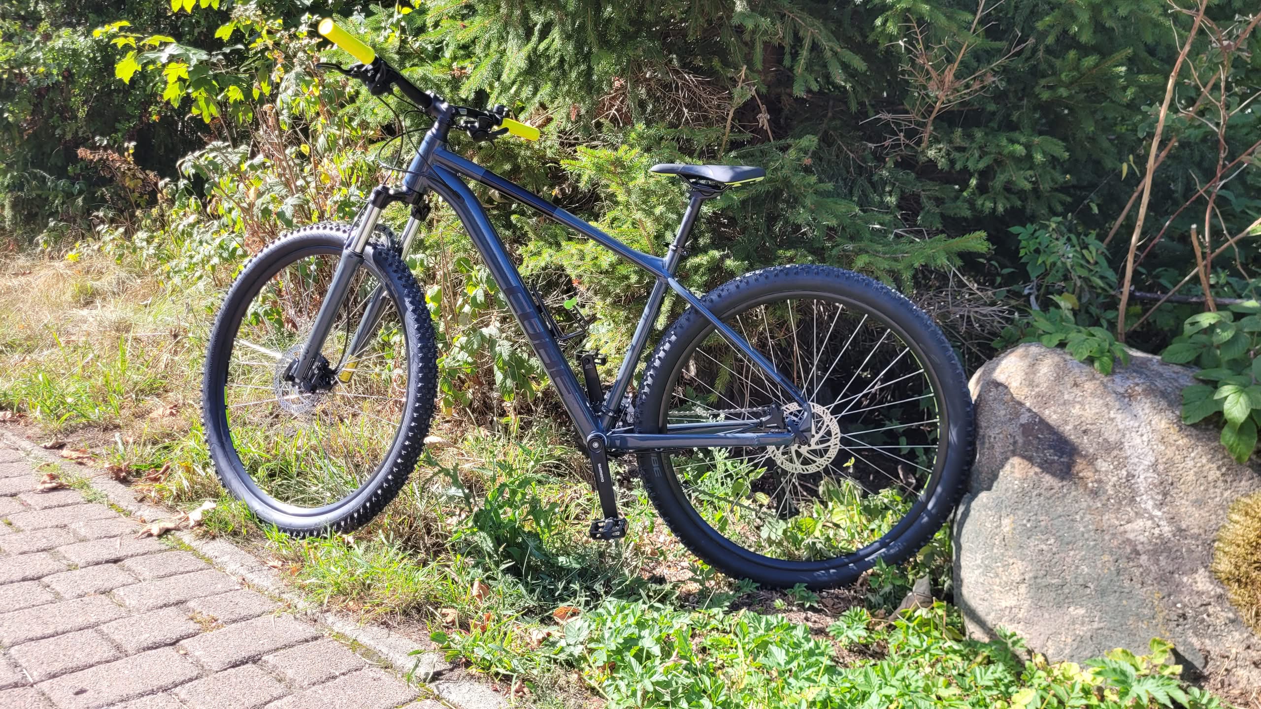 Mountainbike ved vejkanten ved siden af klipper i det grønne