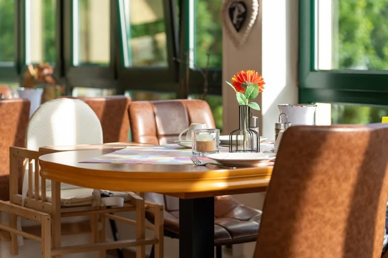 Gemütlicher Frühstückstisch mit orangefarbener Blume