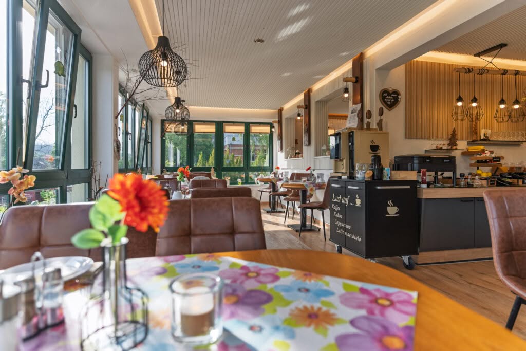 Gemütlicher Frühstücksraum mit großen Fenstern und Holzinterieur