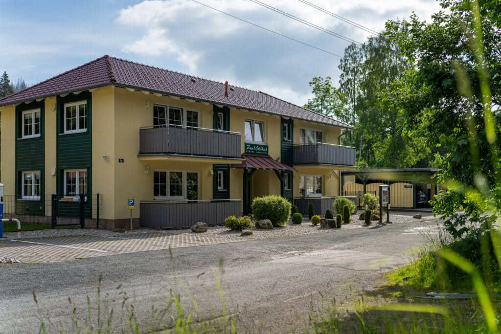 Zweistöckiges Gästehaus mit Balkonen und Parkplatz