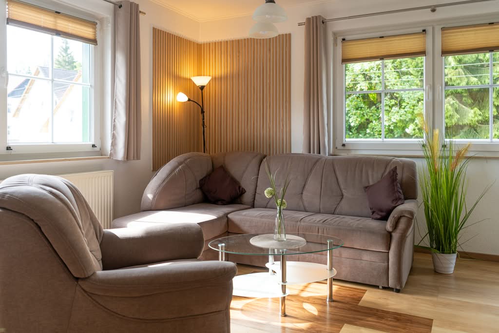 Lys stue med sofa, lænestol og sofabord i glas