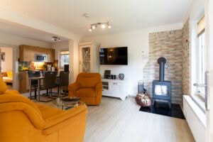 Modernes Wohnzimmer mit Kaminofen und offener Küche