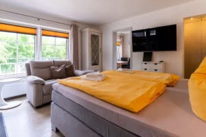 Helles Schlafzimmer mit gelber Bettwäsche und Sofa