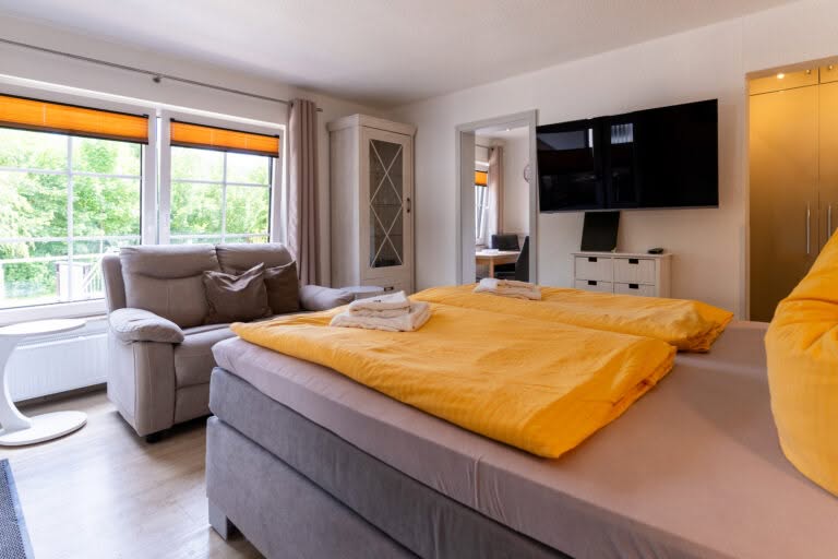 Helles Schlafzimmer mit gelber Bettwäsche und Sofa