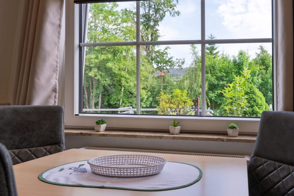 Esstisch vor Fenster mit Blick ins Grüne